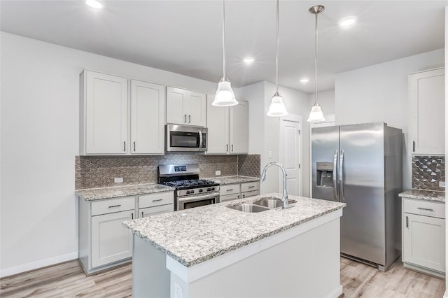 17200C Crane Fly Dr Unit C, Pflugerville, TX 78660 - kitchen with appliances with stainless steel finishes, light wood-style floors, backsplash, a center island with sink, and hanging light fixtures