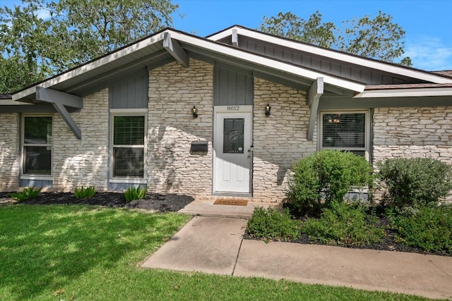 8012 Stillwood Ln, Austin, TX 78757 - entrance to property with stone siding, a lawn, and board and batten siding