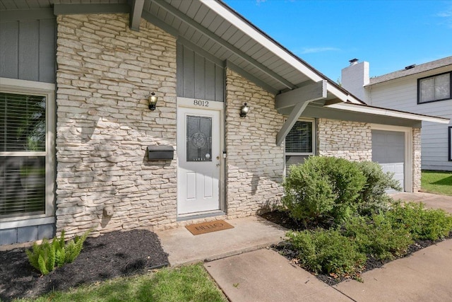 8012 Stillwood Ln, Austin, TX 78757 - view of exterior entry with stone siding, board and batten siding, and an attached garage