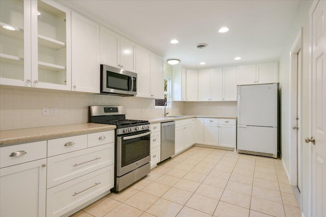 8012 Stillwood Ln, Austin, TX 78757 - kitchen featuring appliances with stainless steel finishes, white cabinetry, decorative backsplash, light countertops, and light tile patterned floors