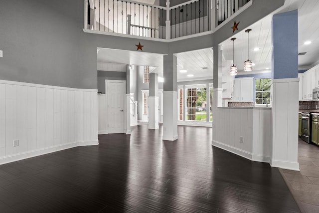 607 County Cork Ln, Leander, TX 78641 - unfurnished living room featuring dark wood-style flooring, a wainscoted wall, and a high ceiling