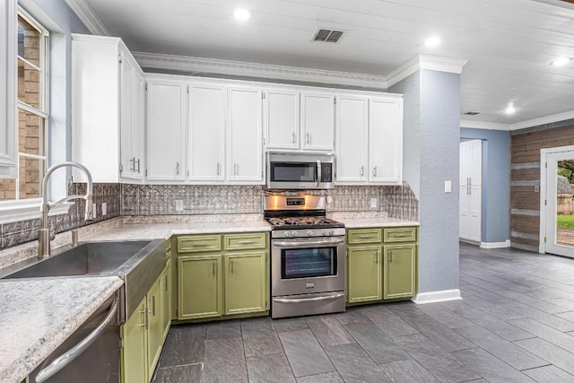 607 County Cork Ln, Leander, TX 78641 - kitchen featuring stainless steel appliances, green cabinetry, crown molding, white cabinetry, and backsplash