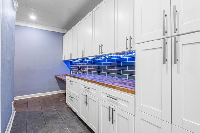 607 County Cork Ln, Leander, TX 78641 - kitchen with backsplash, white cabinetry, ornamental molding, wooden counters, and dark stone finish flooring