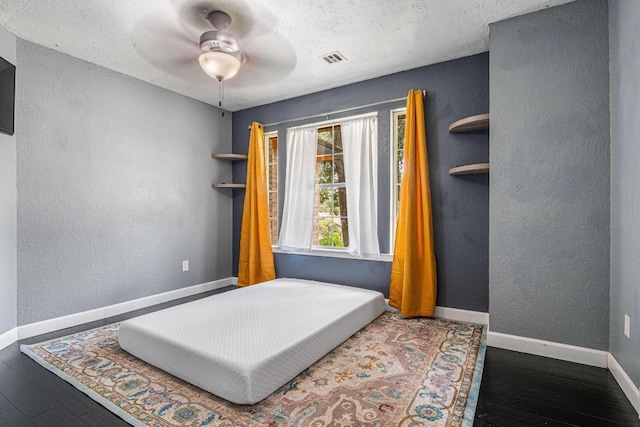607 County Cork Ln, Leander, TX 78641 - bedroom with wood finished floors, a textured wall, a ceiling fan, and a textured ceiling