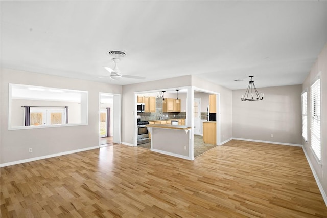 2301 Westworth Cir, Austin, TX 78704 - unfurnished living room featuring light wood-style flooring, a chandelier, and a ceiling fan