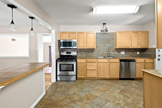 2301 Westworth Cir, Austin, TX 78704 - kitchen featuring stainless steel appliances, light brown cabinets, tasteful backsplash, and pendant lighting