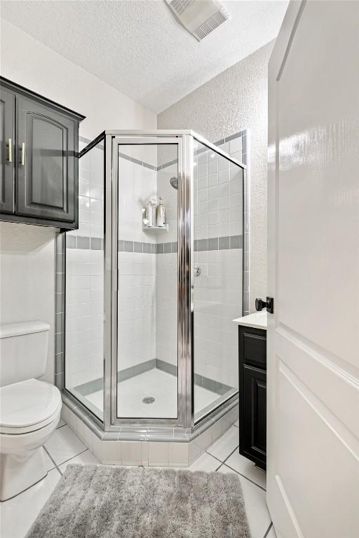 220 Meadow Oaks Dr, Dripping Springs, TX 78620 - full bathroom with a shower stall, a textured ceiling, tile patterned flooring, and a textured wall
