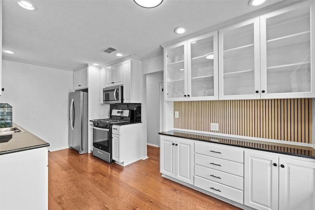 2601 Ashdale Dr, Austin, TX 78757 - kitchen with appliances with stainless steel finishes, white cabinetry, wood finished floors, glass insert cabinets, and recessed lighting