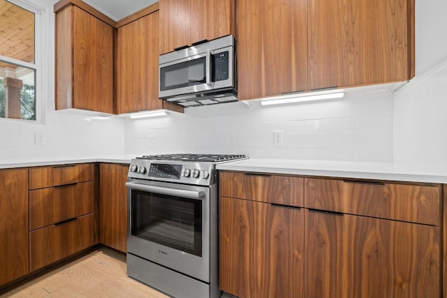 7706 Watson St Unit 2, Austin, TX 78757 - kitchen with stainless steel appliances, modern cabinets, brown cabinetry, light countertops, and backsplash