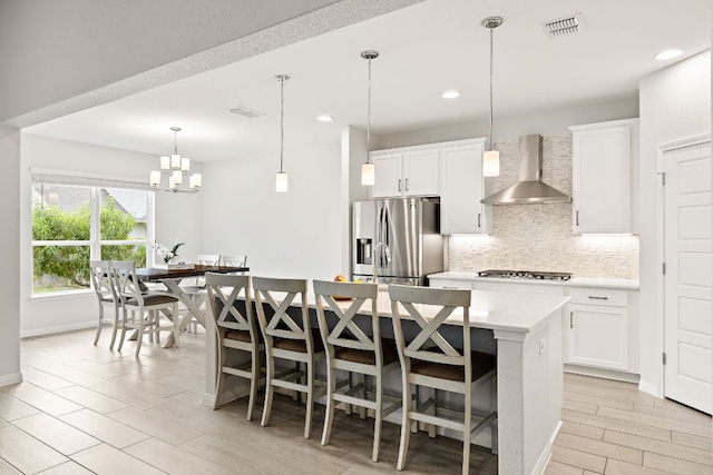 16713 Elsinore Ln, Pflugerville, TX 78660 - kitchen with stainless steel appliances, wall chimney exhaust hood, decorative backsplash, an island with sink, and light countertops
