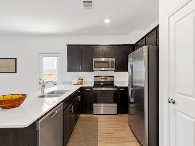 308 Sunfish Ln, Bastrop, TX 78602 - kitchen with stainless steel appliances, a peninsula, light countertops, light wood-type flooring, and dark brown cabinets