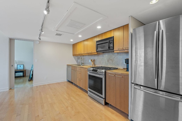 1212 Guadalupe St Unit 805, Austin, TX 78701 - kitchen with appliances with stainless steel finishes, track lighting, light wood-style flooring, recessed lighting, and backsplash