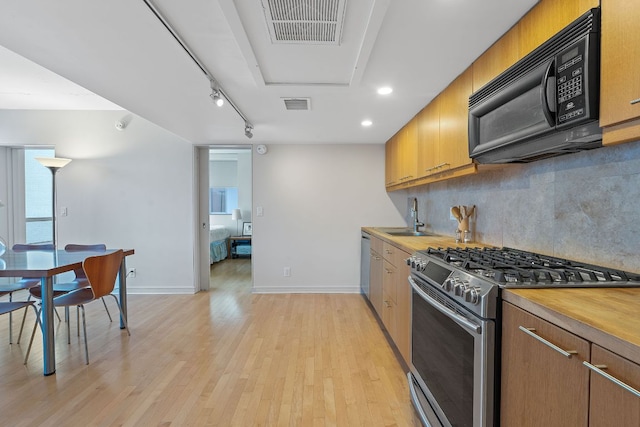1212 Guadalupe St Unit 805, Austin, TX 78701 - kitchen with appliances with stainless steel finishes, light wood-style flooring, decorative backsplash, track lighting, and recessed lighting