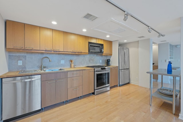 1212 Guadalupe St Unit 805, Austin, TX 78701 - kitchen featuring appliances with stainless steel finishes, light wood-style floors, decorative backsplash, rail lighting, and light countertops