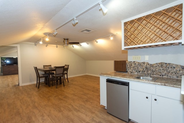 1404 Pearl Cv, Round Rock, TX 78681 - kitchen with stainless steel dishwasher, rail lighting, lofted ceiling, light wood finished floors, and white cabinets