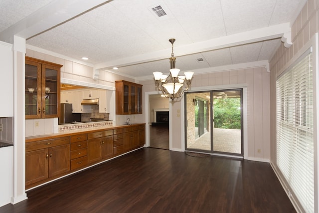 1404 Pearl Cv, Round Rock, TX 78681 - kitchen with brown cabinetry, dark wood-type flooring, a chandelier, glass insert cabinets, and beamed ceiling
