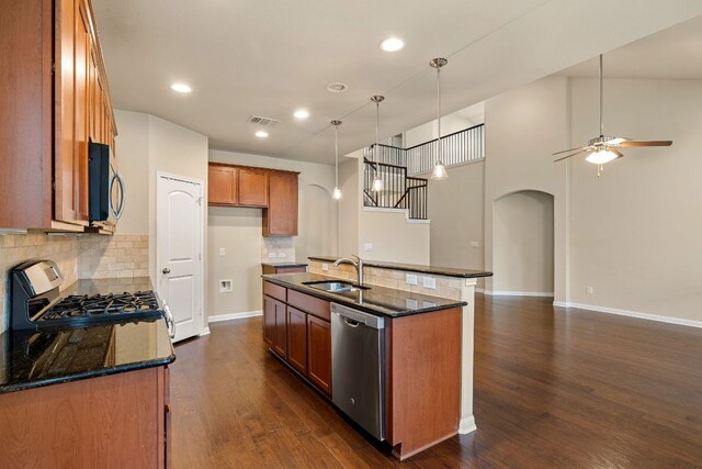 605 Joppa Rd, Leander, TX 78641 - kitchen with stainless steel dishwasher, arched walkways, brown cabinetry, black gas range oven, and dark wood finished floors