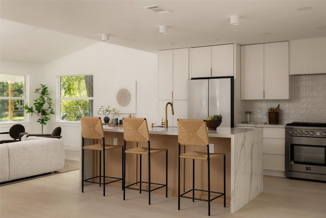 1206 Cloverleaf Dr, Austin, TX 78723 - kitchen with stainless steel appliances, light wood-style flooring, backsplash, a breakfast bar area, and vaulted ceiling