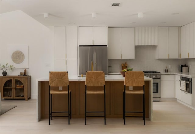 1206 Cloverleaf Dr, Austin, TX 78723 - kitchen featuring appliances with stainless steel finishes, backsplash, white cabinets, light countertops, and light wood-style floors