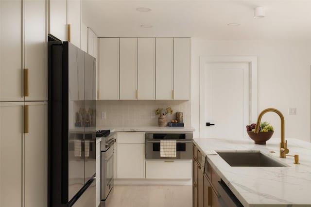 1206 Cloverleaf Dr, Austin, TX 78723 - kitchen featuring stainless steel appliances, decorative backsplash, white cabinetry, and light stone countertops