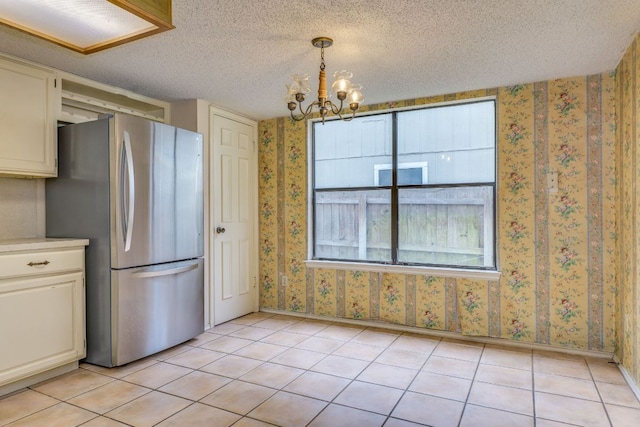 13102 Amarillo Ave, Austin, TX 78729 - kitchen with freestanding refrigerator, a chandelier, light tile patterned floors, wallpapered walls, and light countertops