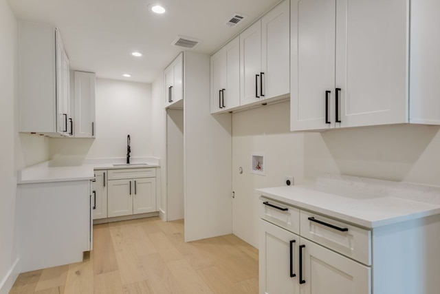 3104 Mistyglen Cir, Austin, TX 78746 - laundry room featuring hookup for a washing machine, light wood-style flooring, electric dryer hookup, recessed lighting, and cabinet space