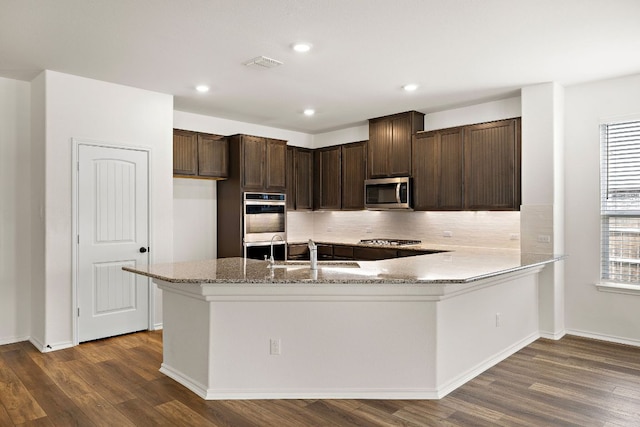 4669 Padula Dr, Round Rock, TX 78665 - kitchen featuring stainless steel appliances, dark wood-type flooring, light stone countertops, dark brown cabinetry, and recessed lighting