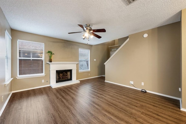 16504 Jadestone Dr, Leander, TX 78641 - unfurnished living room with dark wood-style flooring, ceiling fan, a textured ceiling, a brick fireplace, and stairway