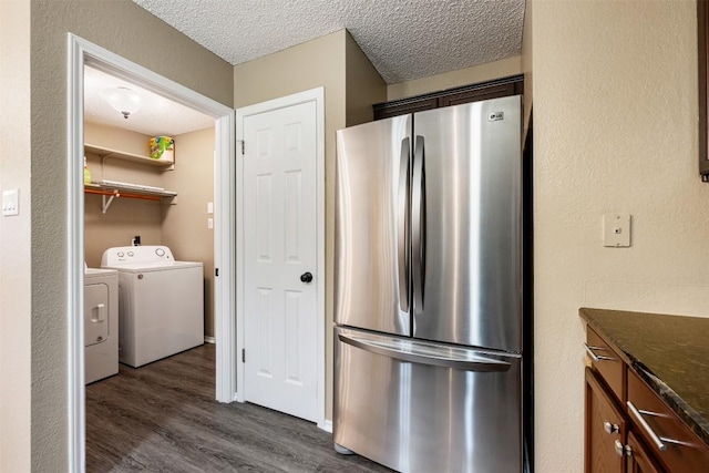 16504 Jadestone Dr, Leander, TX 78641 - kitchen with freestanding refrigerator, independent washer and dryer, dark wood-style flooring, a textured ceiling, and dark stone countertops