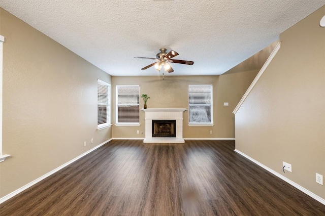 16504 Jadestone Dr, Leander, TX 78641 - unfurnished living room with a ceiling fan, dark wood-type flooring, a fireplace, and a textured ceiling
