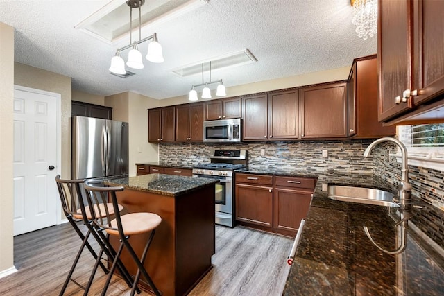 16504 Jadestone Dr, Leander, TX 78641 - kitchen with stainless steel appliances, light wood-type flooring, a center island, a textured ceiling, and decorative backsplash