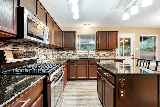 16504 Jadestone Dr, Leander, TX 78641 - kitchen with appliances with stainless steel finishes, decorative backsplash, light wood-type flooring, a textured ceiling, and dark stone counters
