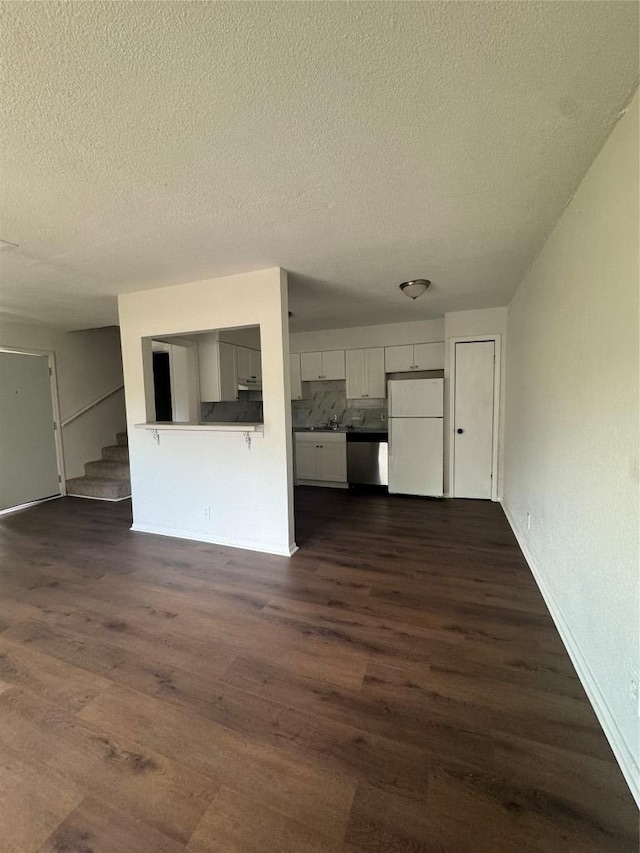 4908 W Gate Blvd, Austin, TX 78745 - unfurnished living room featuring dark wood-type flooring, a textured ceiling, and stairway