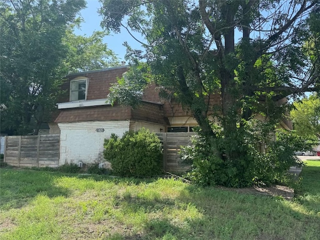 4908 W Gate Blvd, Austin, TX 78745 - view of property exterior with a shingled roof, mansard roof, brick siding, and a yard