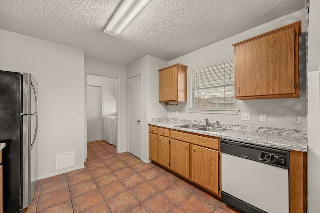 1625 Sylvia Ct, Round Rock, TX 78681 - kitchen featuring white dishwasher, freestanding refrigerator, light countertops, and a textured ceiling