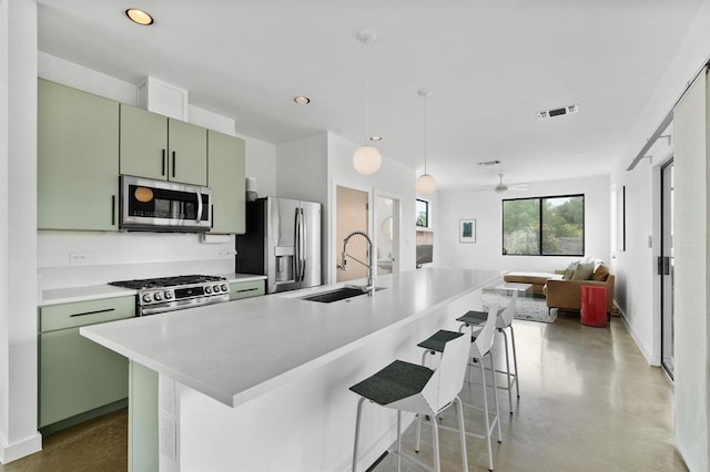 5725 Toscana Ave, Austin, TX 78724 - kitchen featuring stainless steel appliances, green cabinets, light countertops, finished concrete floors, and a kitchen bar