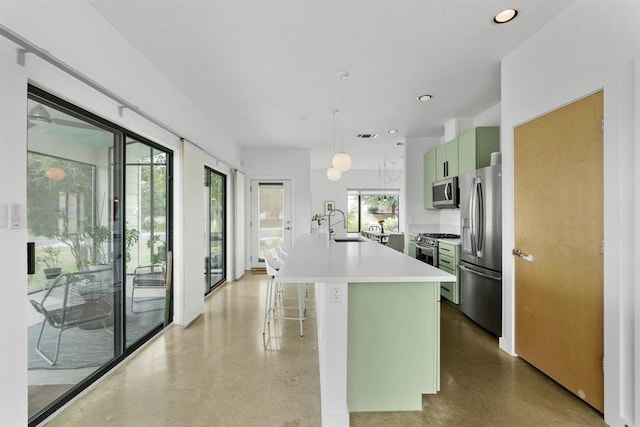 5725 Toscana Ave, Austin, TX 78724 - kitchen with stainless steel appliances, light countertops, a breakfast bar area, a kitchen island with sink, and green cabinetry