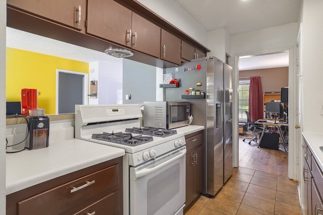 8101 Parkdale Dr, Austin, TX 78757 - kitchen featuring gas range gas stove, an office area, stainless steel microwave, light countertops, and light tile patterned floors