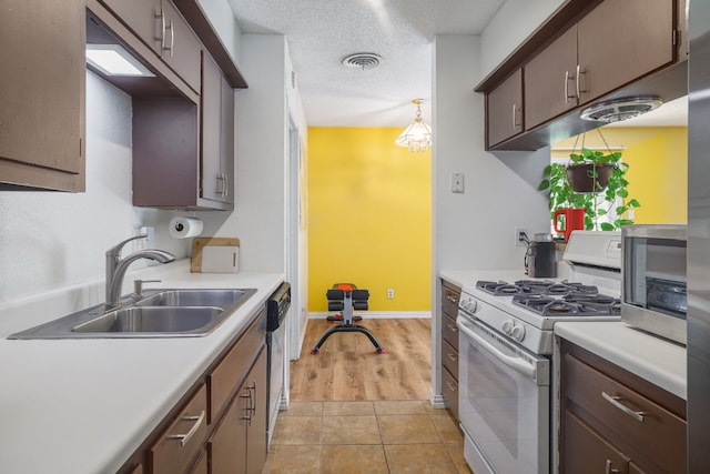 8101 Parkdale Dr, Austin, TX 78757 - kitchen with white gas stove, light countertops, stainless steel dishwasher, and light tile patterned flooring