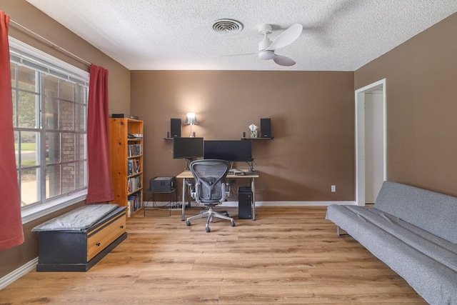 8101 Parkdale Dr, Austin, TX 78757 - home office featuring wood finished floors, healthy amount of natural light, a textured ceiling, and a ceiling fan