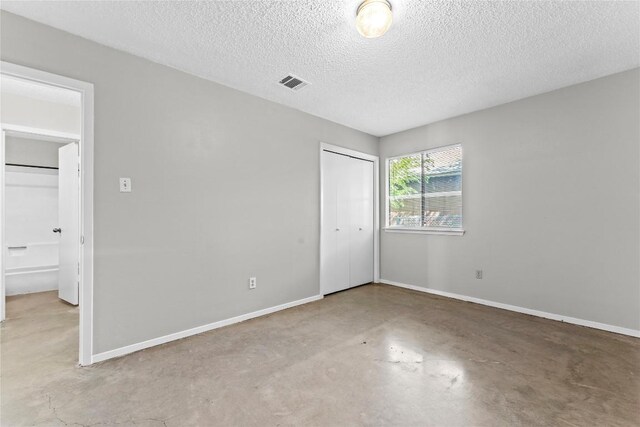 6201 Berkett Cv, Austin, TX 78745 - unfurnished bedroom with finished concrete floors, a textured ceiling, and a closet