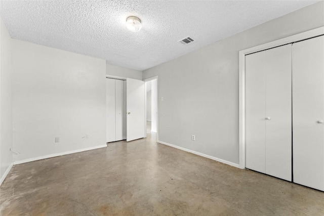 6201 Berkett Cv, Austin, TX 78745 - unfurnished bedroom with two closets, concrete flooring, and a textured ceiling