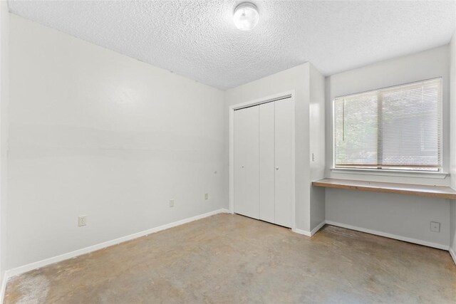 6201 Berkett Cv, Austin, TX 78745 - unfurnished bedroom featuring a textured ceiling, concrete flooring, and a closet