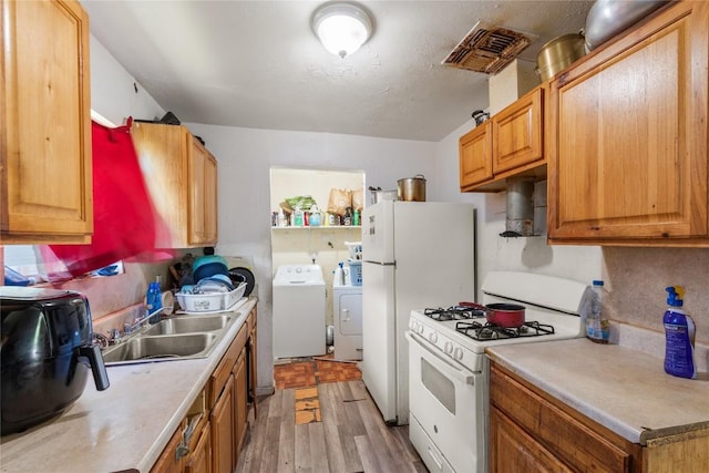 7105 Bethune Ave, Austin, TX 78752 - kitchen featuring white appliances, separate washer and dryer, light wood-style floors, and light countertops