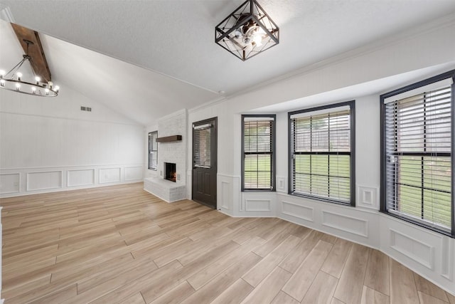 1107 Timmons Dr, Copperas Cove, TX 76522 - unfurnished living room with a chandelier, a decorative wall, plenty of natural light, light wood-style flooring, and a brick fireplace