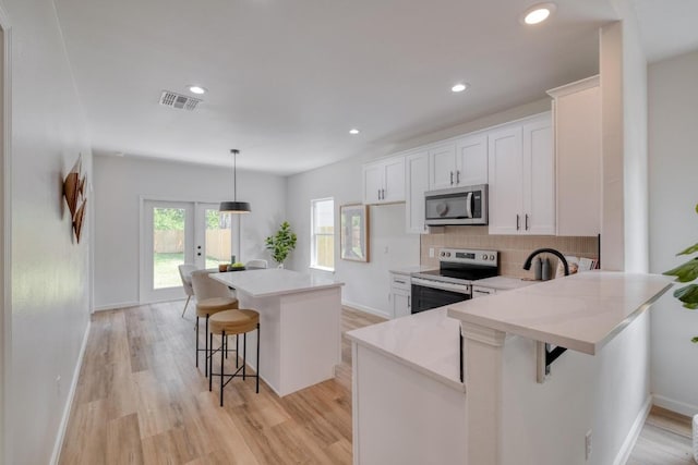 815 Fir Ln, Lockhart, TX 78644 - kitchen featuring stainless steel appliances, a kitchen bar, white cabinetry, light countertops, and recessed lighting