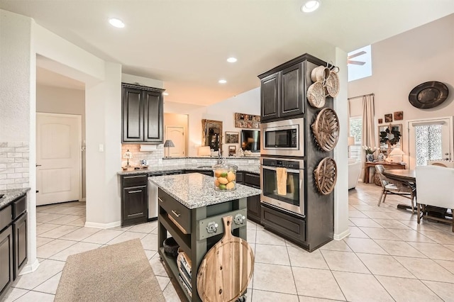 18920 Still Pond Rd, Pflugerville, TX 78660 - kitchen featuring stainless steel appliances, tasteful backsplash, light stone countertops, a center island, and light tile patterned floors