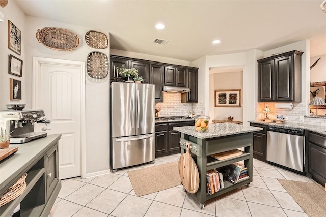 18920 Still Pond Rd, Pflugerville, TX 78660 - kitchen featuring appliances with stainless steel finishes, under cabinet range hood, tasteful backsplash, light tile patterned floors, and recessed lighting