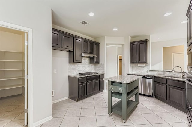 18920 Still Pond Rd, Pflugerville, TX 78660 - kitchen with appliances with stainless steel finishes, under cabinet range hood, decorative backsplash, light tile patterned floors, and recessed lighting