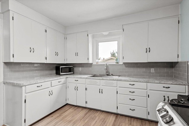 17205 County Line Rd, Elgin, TX 78621 - kitchen with range, light countertops, stainless steel microwave, white cabinetry, and tasteful backsplash